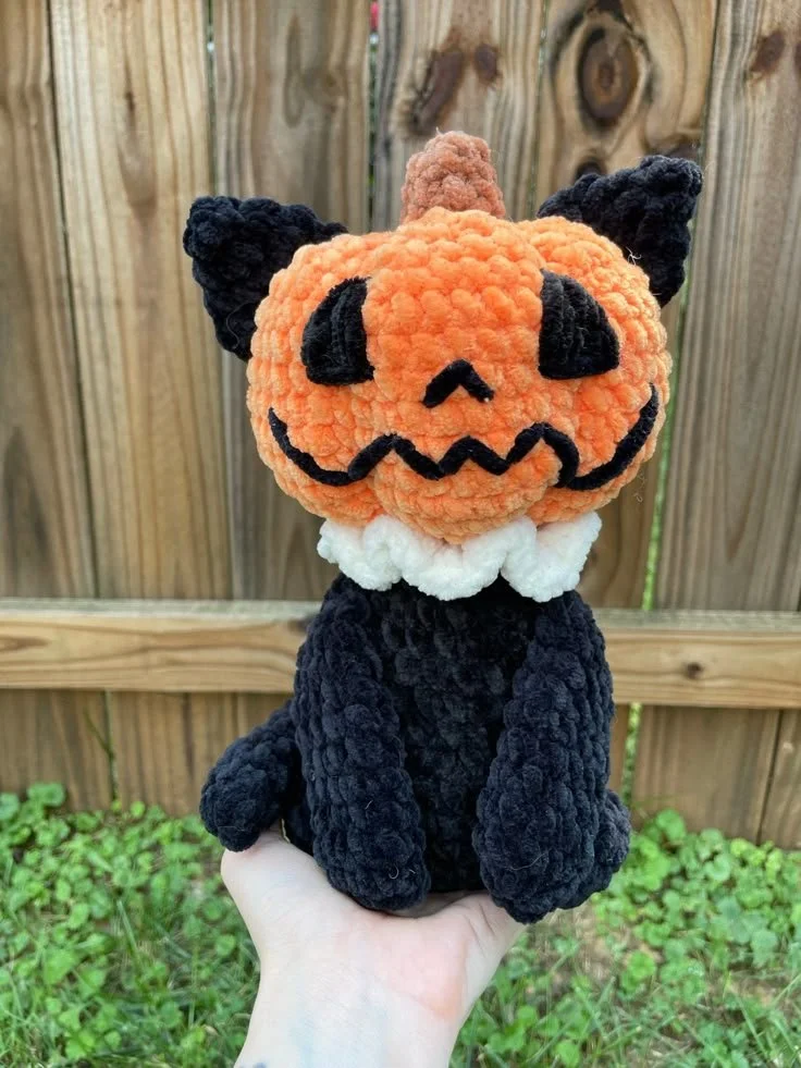 Crocheted pumpkin cat decoration perfect for fall decor.